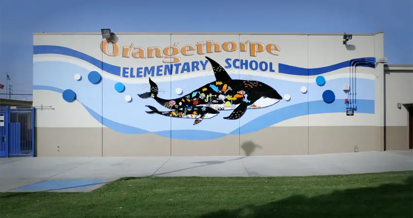 A mural of two dolphins on the side of an elementary school.