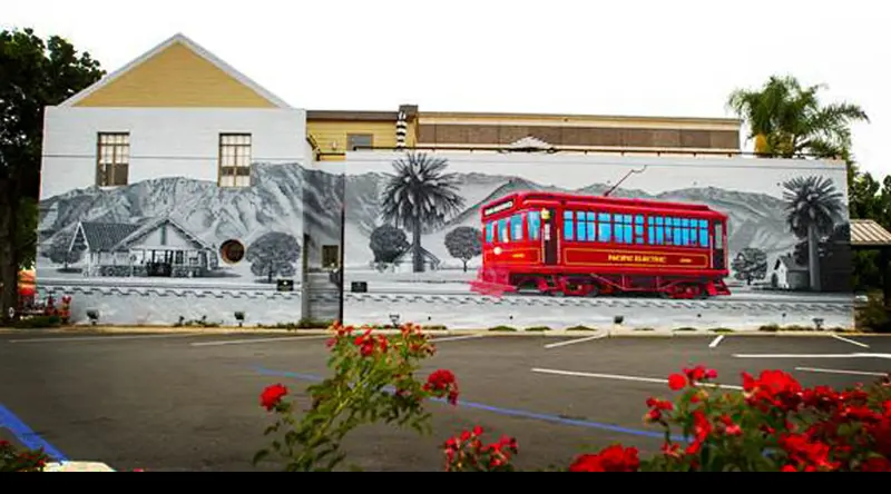 A red trolley train mural on the side of a building.